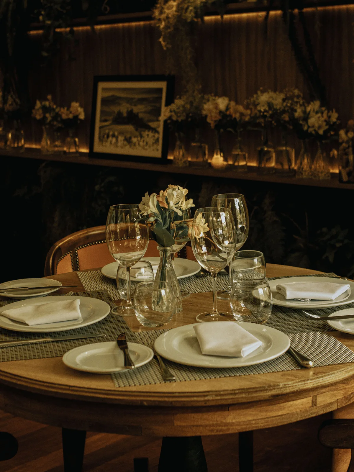 Mesa de restaurante preparada para recibir clientes, con iluminación cálida y copas dispuestas.